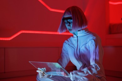 woman with futuristic tablet in hand. girl in glasses of virtual reality. augmented reality, future technology, ai concept. holographic interface to display data. smart home background.