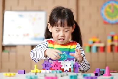 young girl playing gear toy blocks at home