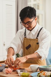 smiling sushi master portrait at work. still life male chef makes sushi and rolls from rice on kitchen. asian food delivery concept 