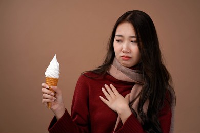 asian woman with vanilla ice cream cone , winter outfit wear red sleeves and pink scarf, isolated brown  background