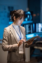 young asian businesswoman in formalwear scrolling in tablet while searching in the net for new methods of decoding digital data