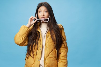 fashionable woman in winter jacket glasses modern style blue background