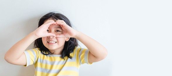 healthy eyes and vision.portrait happy asian kid child holding heart shaped hands on eyes.smiling girl with healthy skin showing love sign. eye care.carotene vitamin.focus, optician doctor, optical.