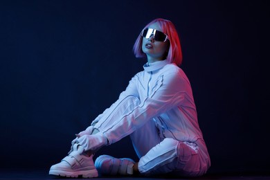 woman in futuristic costume. female in modern vr glasses interacting with network while having virtual reality experience. augmented reality game, future technology, ai concept. vr. neon blue light.