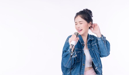 cheerful young woman holding microphone in own hands enjoyment sing song while standing over isolated white background. lifestyle hobby entertainment concept.