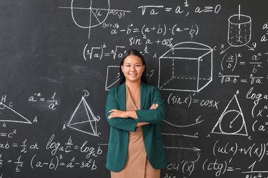 asian female teacher near blackboard in classroom