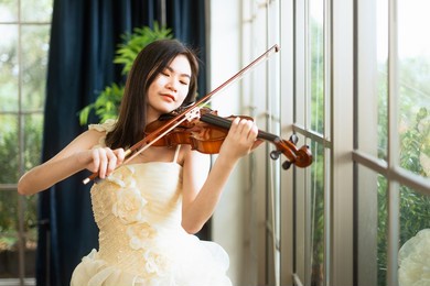asian women play the violin indoor. portrait of a female violinist who is playing a string instrument.