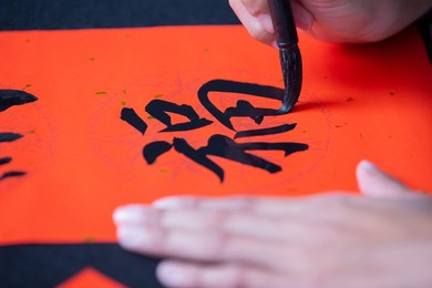 asian people write calligraphy on couplet to celebrate chinese new year with word meaning luck