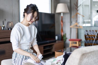 young woman folding laundry at home