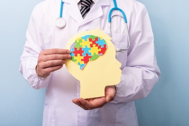 doctor hands holding head with jigsaw puzzle brain shape. autism spectrum disorder concept. world autism awareness day.