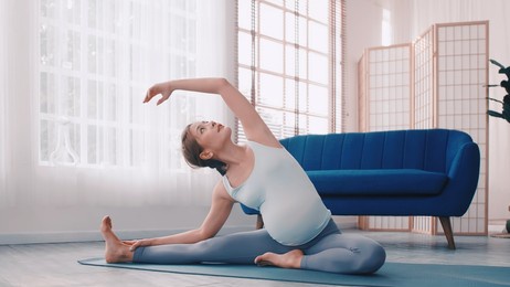 asian pregnant woman doing yoga exercises at home.