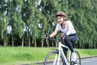 asian young sport woman riding bicycle in the evening in public park. beautiful athlete fit and firm girl in sportswear wear helmet, exercise by cycling workout for her health care wellness and fresh.