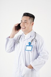 portrait of positive doctor in white labcoat putting hand in pocket and talking on phone with patient