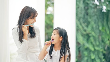 asian girl brushing her teeth with mom. dental care. oral care.