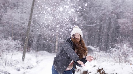 happy young woman in a snowball fight. winter holiday spirit. 