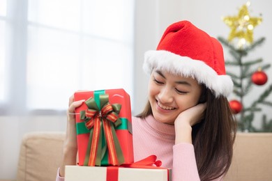 happy beautiful asian woman celebrate with stacking many present gift box in christmas party. cute girl in christmas holiday holding gift box decorated with ribbon and bow. happy new year festival.