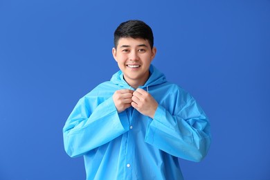 young asian man in raincoat on color background