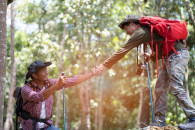 fellow help his frient to climbing up to the top of hill with happiness, friendship between hilking journey concept.