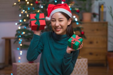 happy smiling young asian woman in santa claus hat holding many gift box celebrate christmas and new year