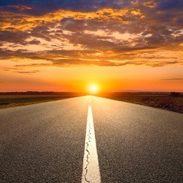 driving on an empty asphalt road towards the sunset