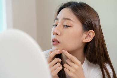 dermatology, puberty asian young woman, girl looking into mirror, allergy when wear mask and cosmetic, show squeezing pimple spot for removing from face.beauty care from skin problem by acne treatment