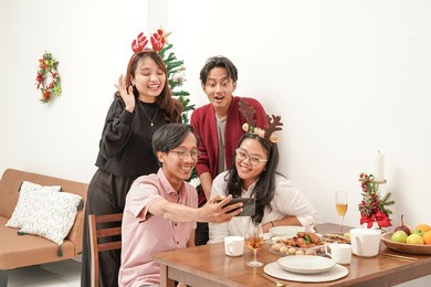 four asian people taking a picture after celebrating christmas and eating together. they looks very happy. merry christmas everyone!                             
