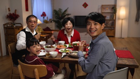 slow motion of happy family at dinner table turning head and look at camera in surprise as someone is serving the main dish for reunion meal at home