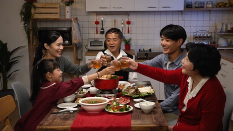 cheerful chinese family with mixed generation raising glasses to toast new year as they are gathering to have reunion dinner in celebration of spring festival at home