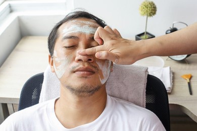 man having cosmetic mask in spa salon