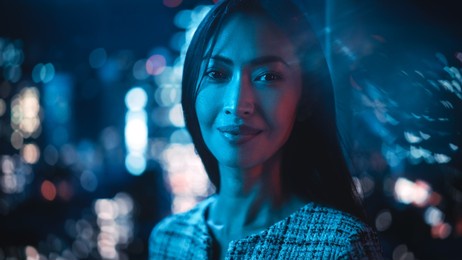 beautiful asian female portrait standing on city street with neon lights late in the evening. authentic adult confident woman posing for camera, smiling in the night on downtown business street.