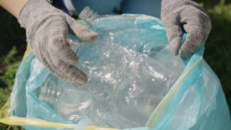 hand puts a plastic bottle in a bag, garbage for processing, eco, keep the environment clean, green planet safe, nature forest ecosystem, environmental protection problem, charitable activities