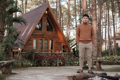 happy man in sweater traveling in pine tree forest, tourist visit at doi bo luang, chiang mai, thailand, landmark and popular for tourist attractions. vacation and journey concept