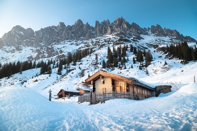 beautiful panorama view of scenic winter wonderland mountain scenery in the alps with traditional mountain huts illuminated in last evening light at sunset, mühlbach am hochkönig, salzburg, austria