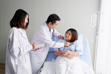 a doctor and a female doctor are examining a patient lying on a hospital bed.