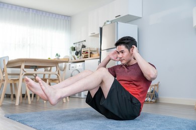 asian attractive active young man doing floor exercise in living room. handsome male in sport cloth spend leisure activity time for exercise workout in vacation at home. healthy lifestyle concept.