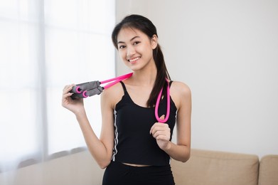 young beautiful asian woman standing pose smiling to camera. cheerfully sporty female workout and exercise wearing sport wear at home. charming woman fitness training and stretching in living room
