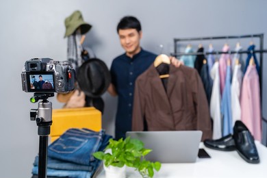 young man selling hat and clothes online by camera live streaming, business online e-commerce at home
