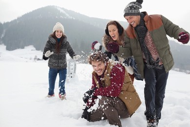 playful friends enjoying snowball fight in field