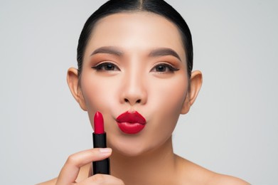 portrait of beautiful asian woman with lipstick in hand. skin care healthy hair and skin close up face beauty isolated over background. cosmetology and spa concept.
