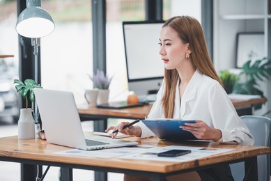 asian woman sitting at a desk working in the office use a computer, laptop
