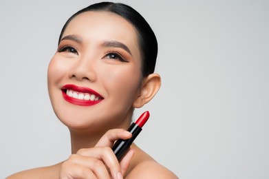 portrait of beautiful asian woman with lipstick in hand. skin care healthy hair and skin close up face beauty isolated over background. cosmetology and spa concept.