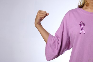 woman wearing a purple ribbon and showing a strong gesture for cancer awareness day