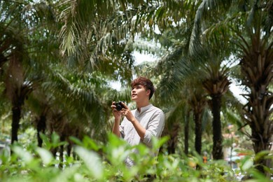 young asian tourist man smiling happy using vintage camera at the city.