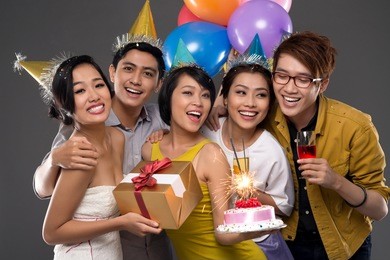 joyful friends with cake and gift at the birthday party