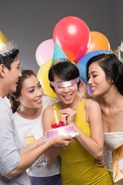 vietnamese young people presenting a cake to their blindfolded friend