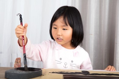 the little oriental girl dipped ink in the inkstone with a brush