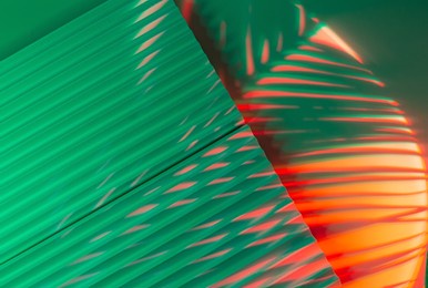palm tree leaves on abstract background with podiums in neon light. trendy geometric shapes for products. red and green gradient light. minimalism, 90s, 80s concept.