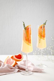 glasses of tasty grapefruit cocktail on light background