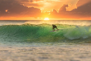 surfer at sunrise with perfect wave