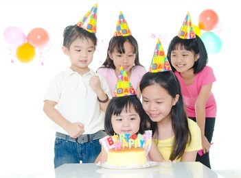 group of adorable kids looking at birthday cake with candles